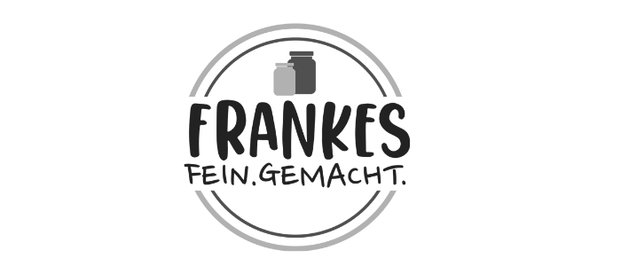 Ein kreisförmiges Logo mit dem Text „FRANKES FEIN.GEMACHT.“ in der Mitte. Darüber sind zwei Gläser abgebildet. Das Design ist in Graustufen gehalten und wirkt schlicht und modern.